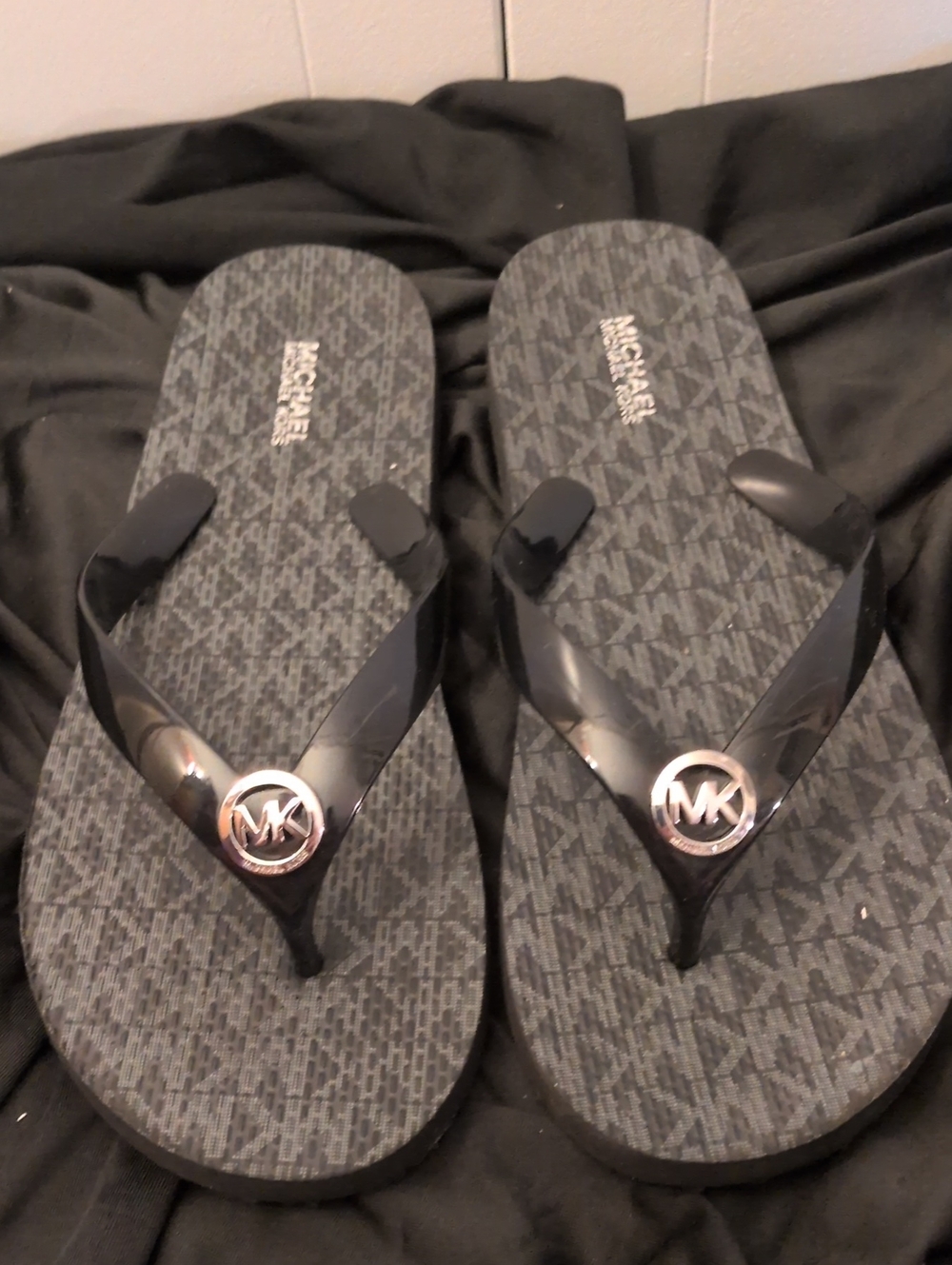 Michael Kors Black Logo Monogram Flip Flops with Silver MK Medallions.